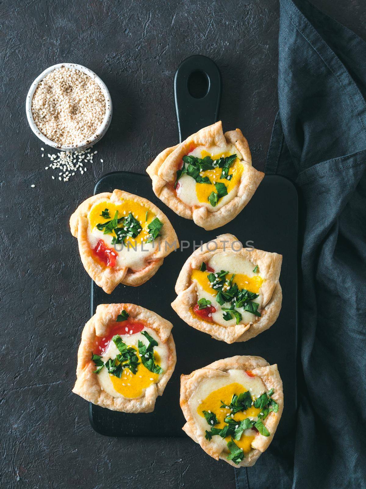 Ideas and recipes for healthy Vegan Shakshouka cups with vegan tofu eggs and turmeric yolk. Ready-to-eat. Puff filo pastry,tomato sauce and green parsley. Top view or flat lay. Copy space. Vertical