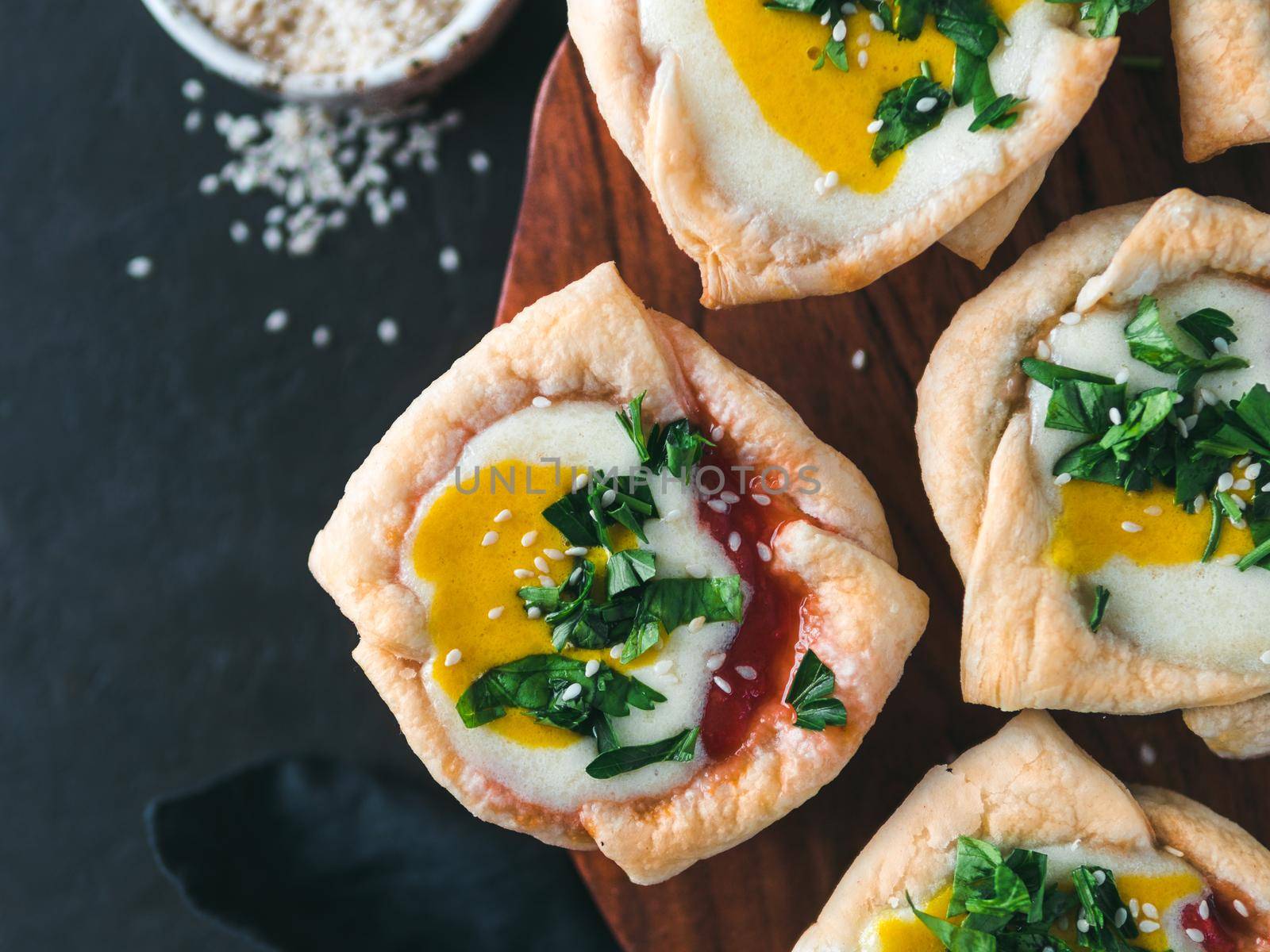 Ideas and recipes for healthy Vegan Shakshouka cups with vegan tofu eggs and turmeric yolk. Puff filo pastry,tomato and vegetable sauce and fresh green parsley.Top view or flat lay.Copy space for text