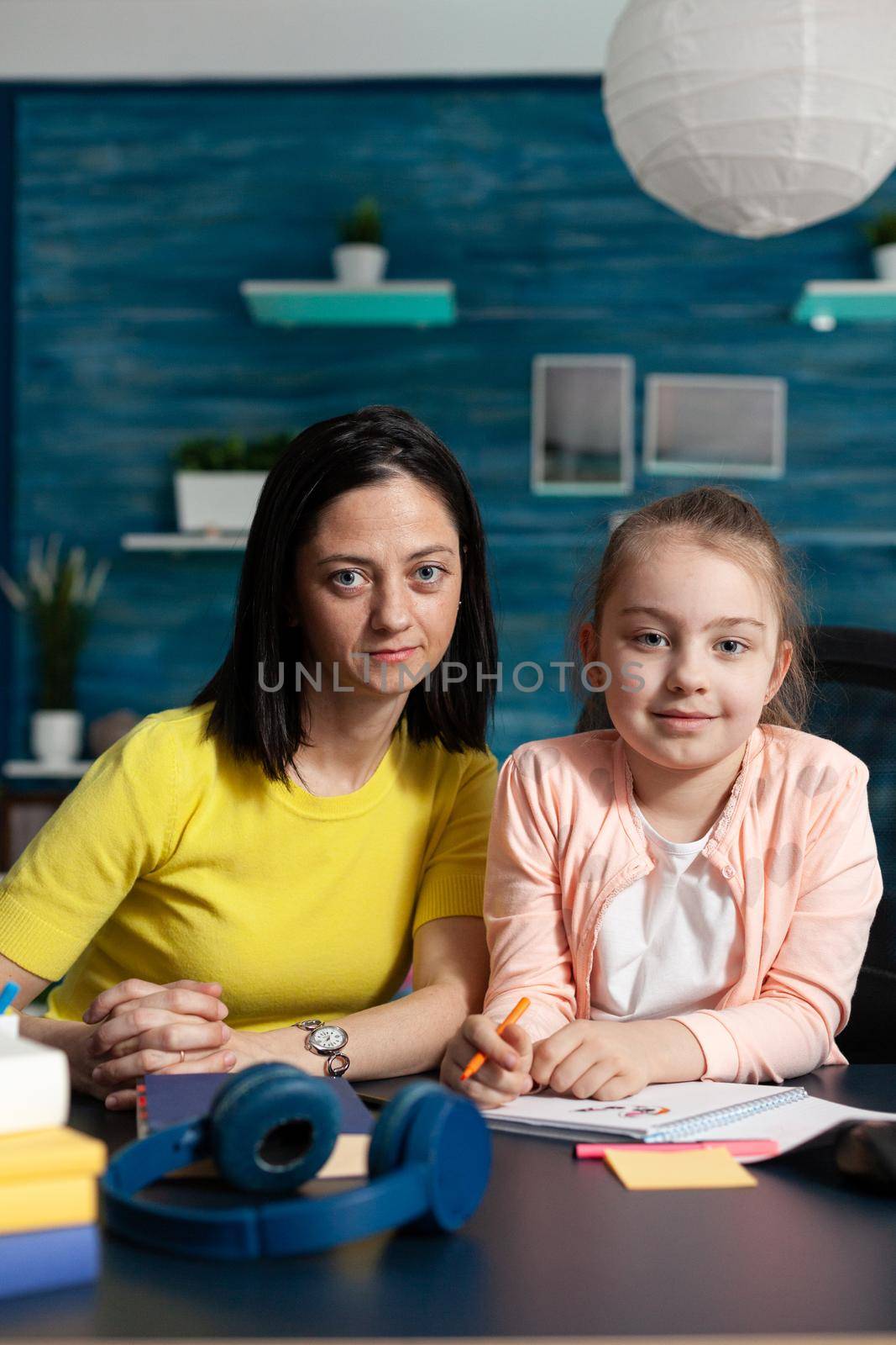 Portrait of smiling family looking into camera while sitting at desk by DCStudio