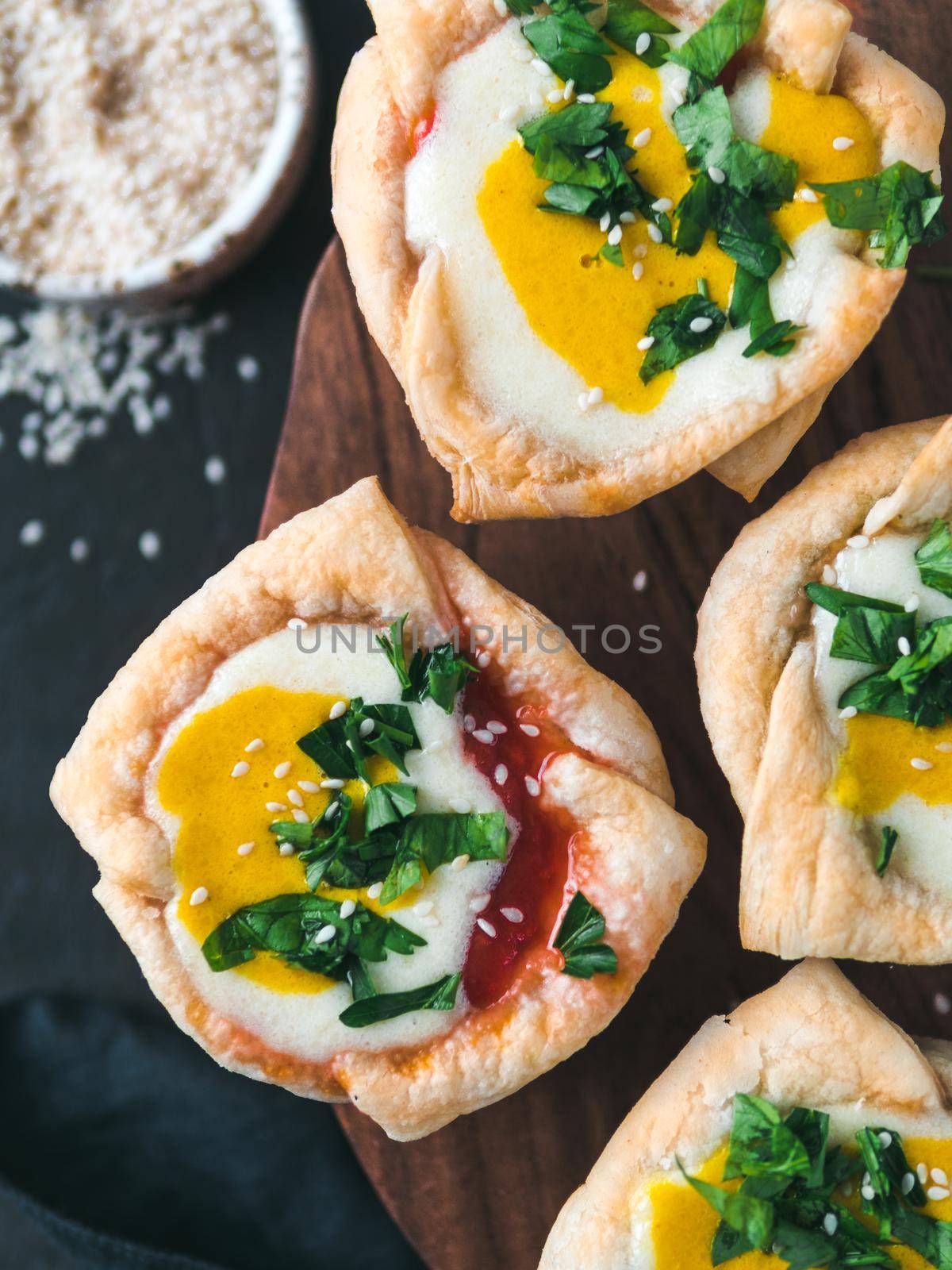 Ideas and recipes for healthy Vegan Shakshouka cups with vegan tofu eggs and turmeric yolk. Puff filo pastry,tomato and vegetable sauce and fresh green parsley.Top view or flat lay. Vertical