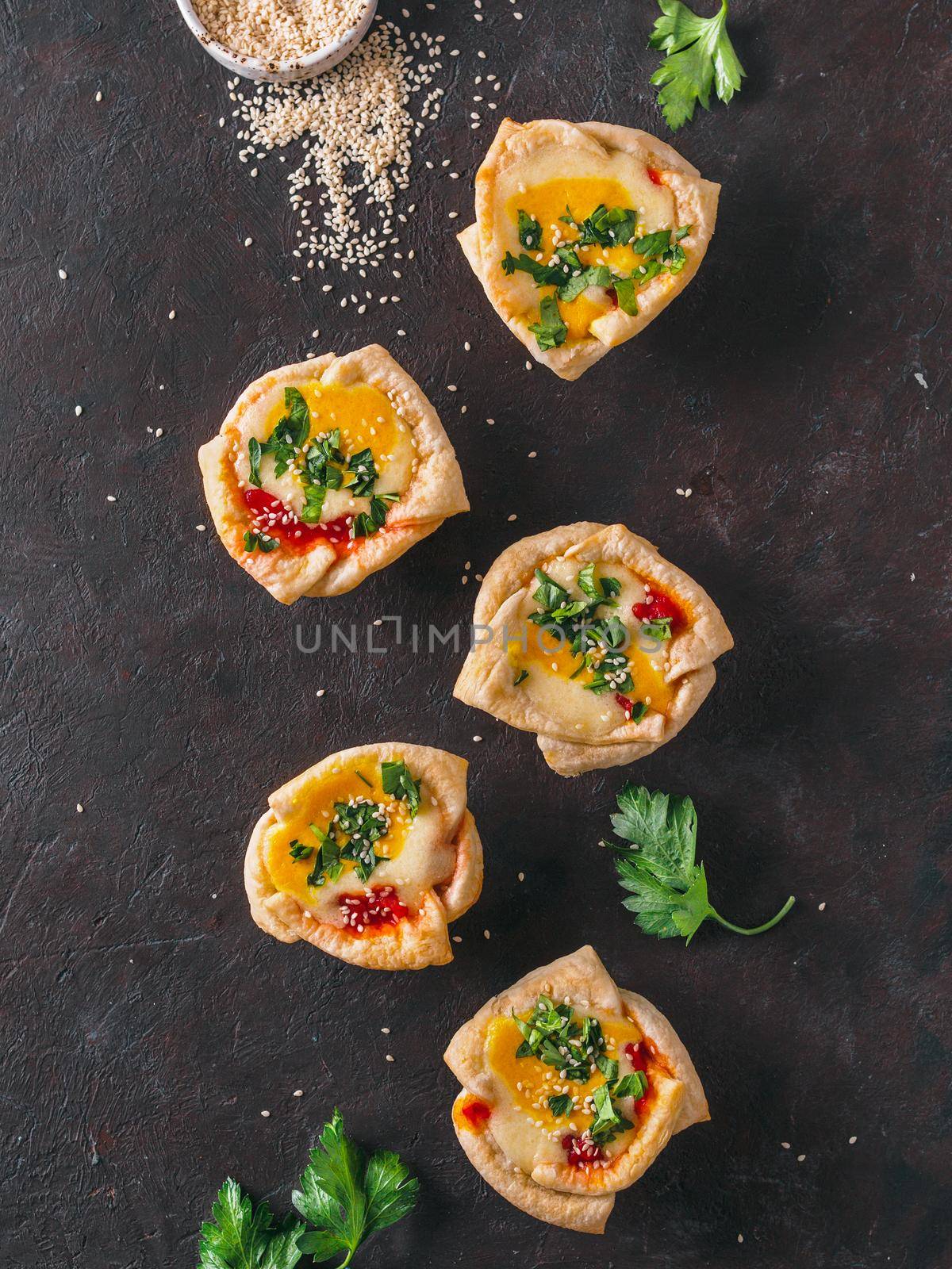 Ideas and recipes for healthy Vegan Shakshouka cups with vegan tofu eggs and turmeric yolk. Puff filo pastry,tomato sauce and green parsley.Top view or flat lay.Copy space for text. Vertical.