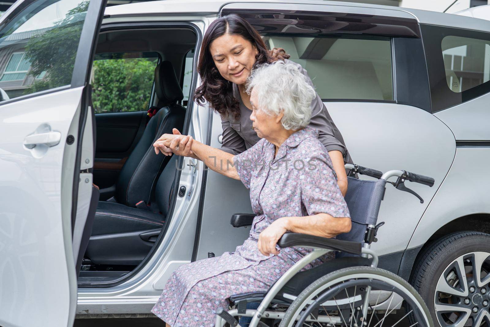 Help and support asian senior or elderly old lady woman patient sitting on wheelchair prepare get to her car, healthy strong medical concept.