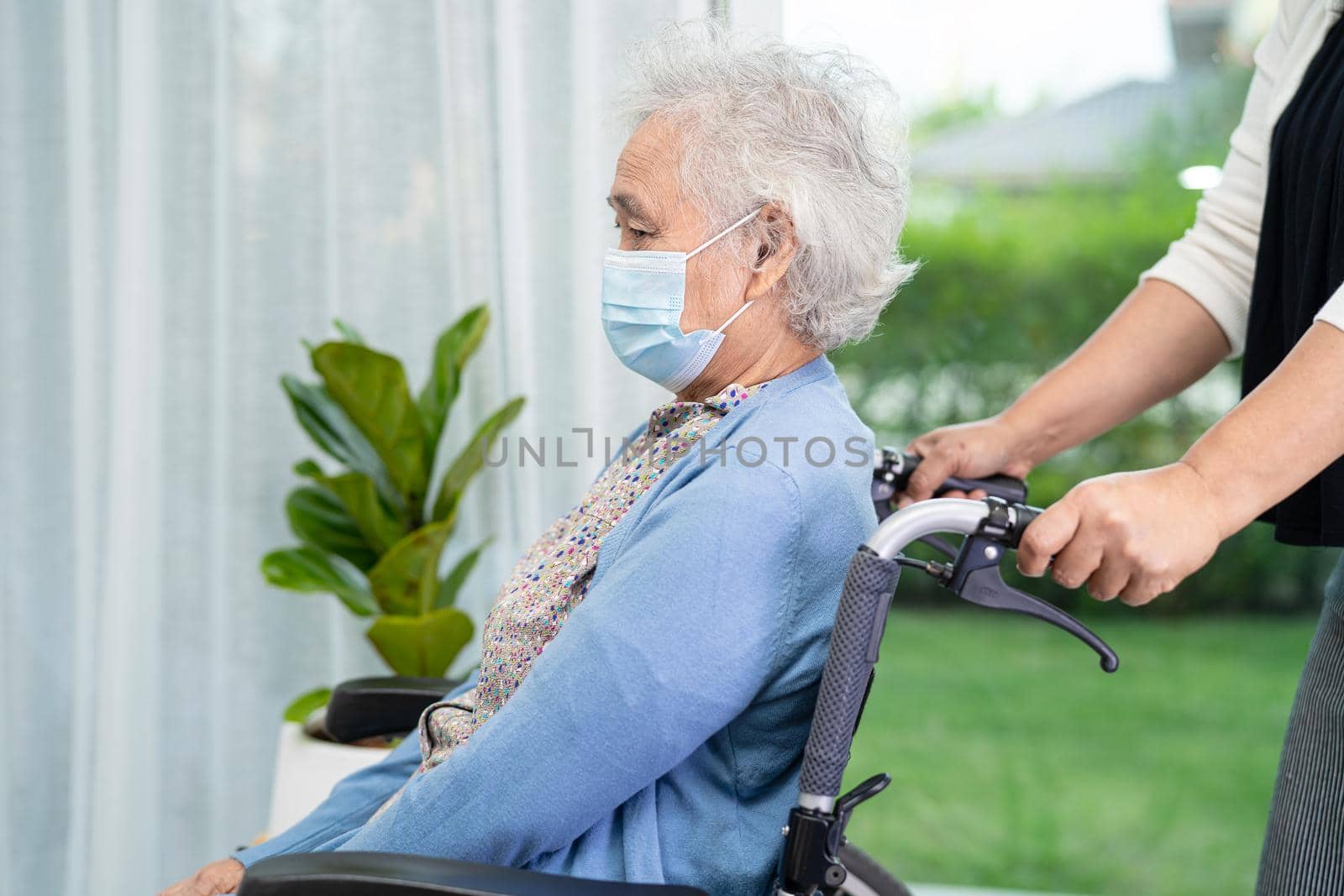 Help Asian senior or elderly old lady woman sitting on wheelchair and wearing a face mask for protect safety infection Covid-19 Coronavirus.