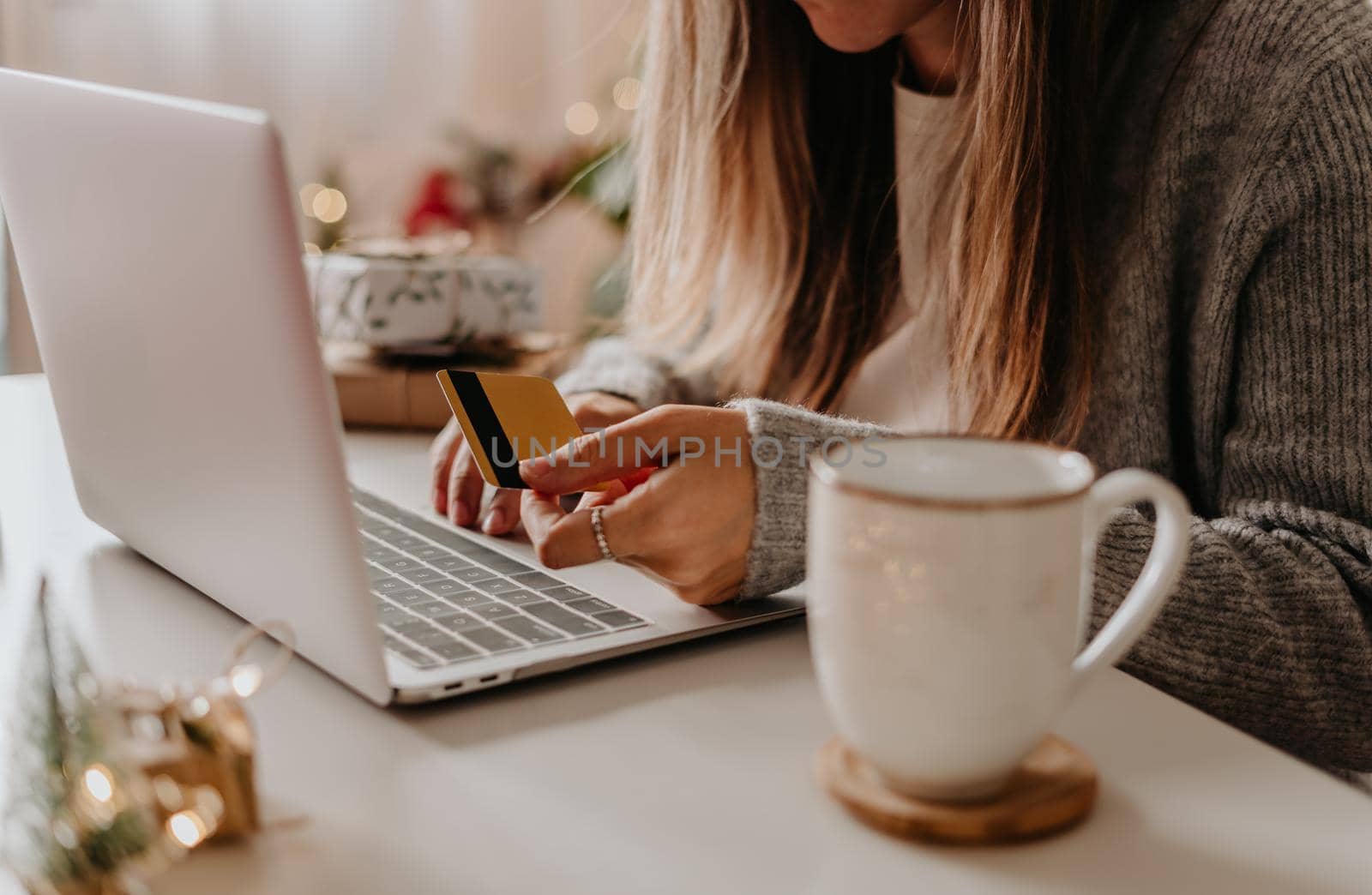Close up of woman hands with credit card, gifts, coffee cup and laptop. Online shopping at Christmas holidays. Freelance girl woking from home office