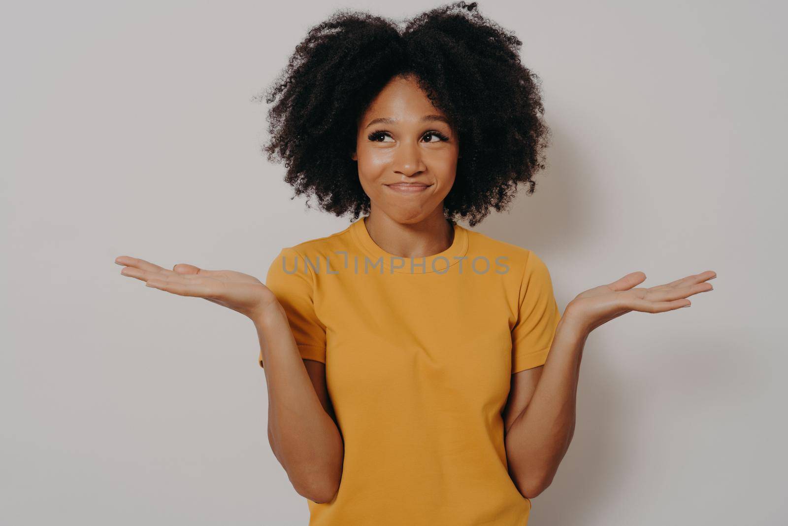 Young african woman standing with clueless and funny confused expression with arms and hands raised by vkstock