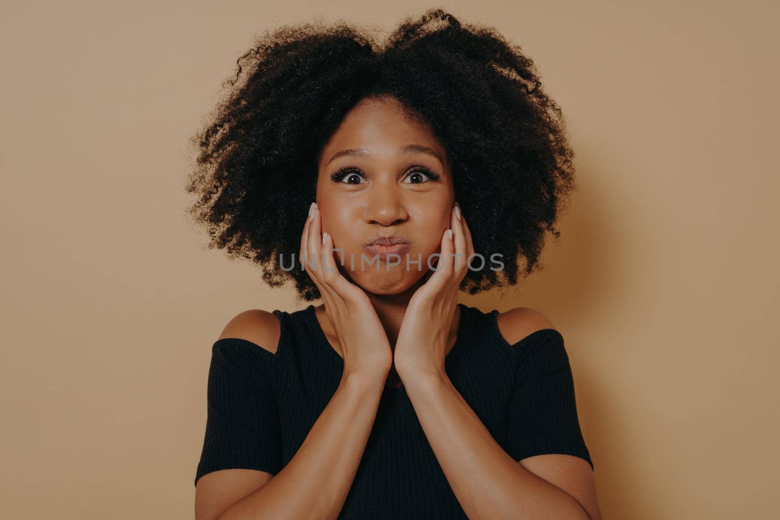 Indoor portrait of glamorous african model isolated on dark beige background with copy space by vkstock