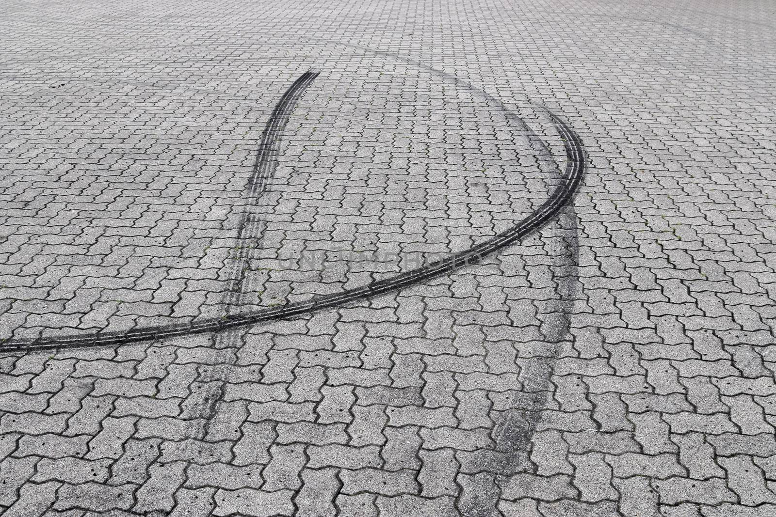 Black tire tracks on a cobblestone road