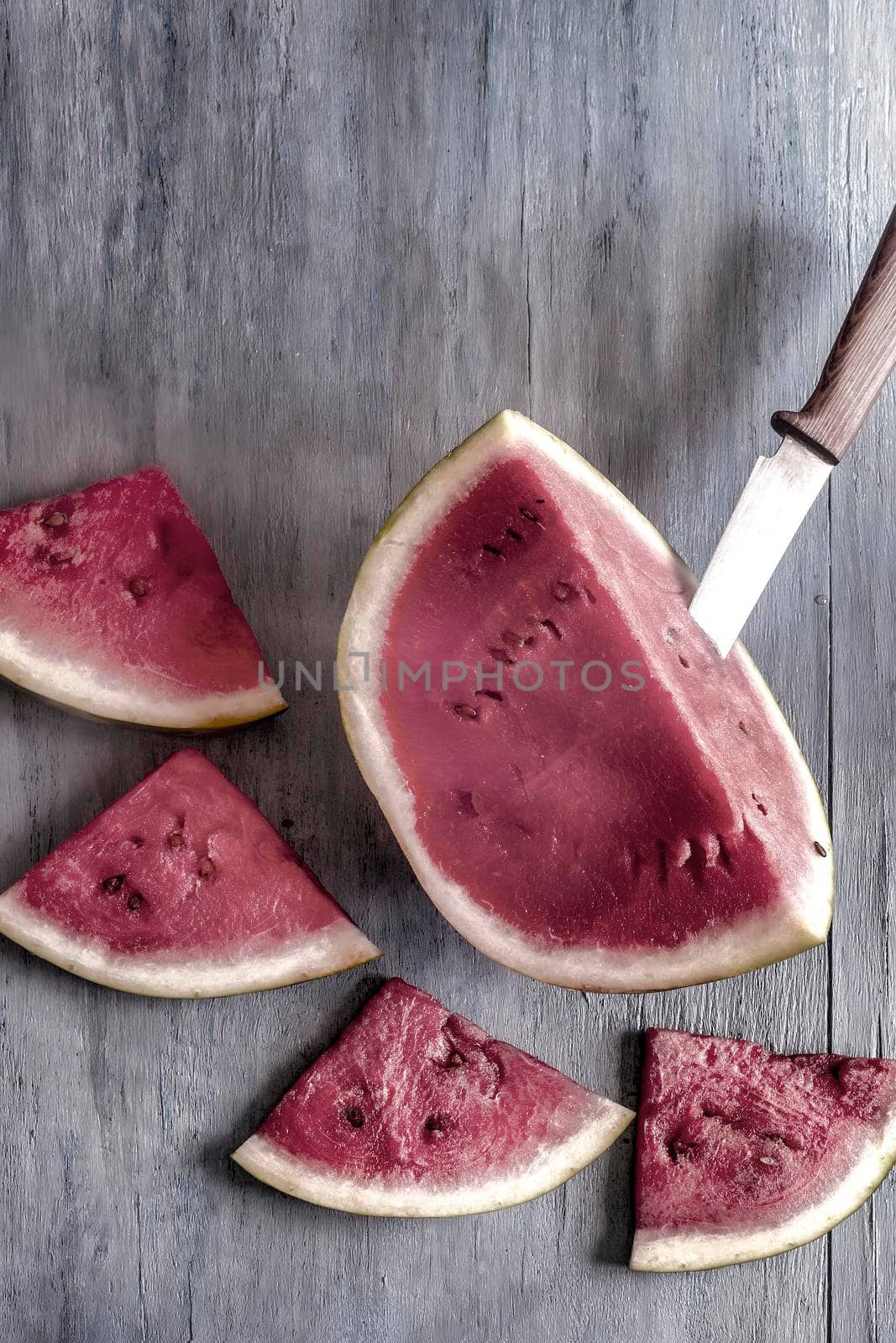 Sliced watermelon slices are lying on the wooden surface of the table. Top view, close-up, copy space