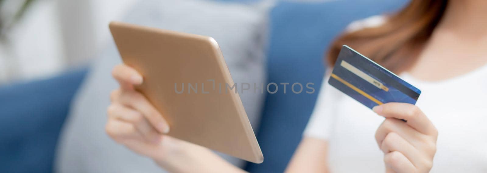 Young asian woman smiling holding credit card shopping online with tablet computer buying and payment, girl using debit card purchase or transaction of finance, lifestyle and e-commerce concept.