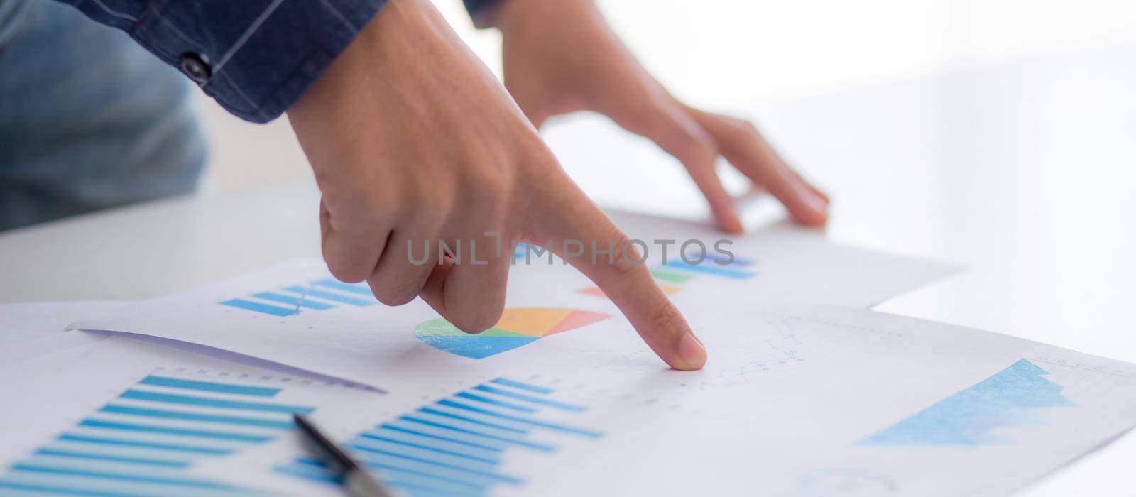 Hand of young business man pointing document data graph and chart paper, marketing and investment, report of statistics profit for financial, economic and growth of finance, management and planning. by nnudoo