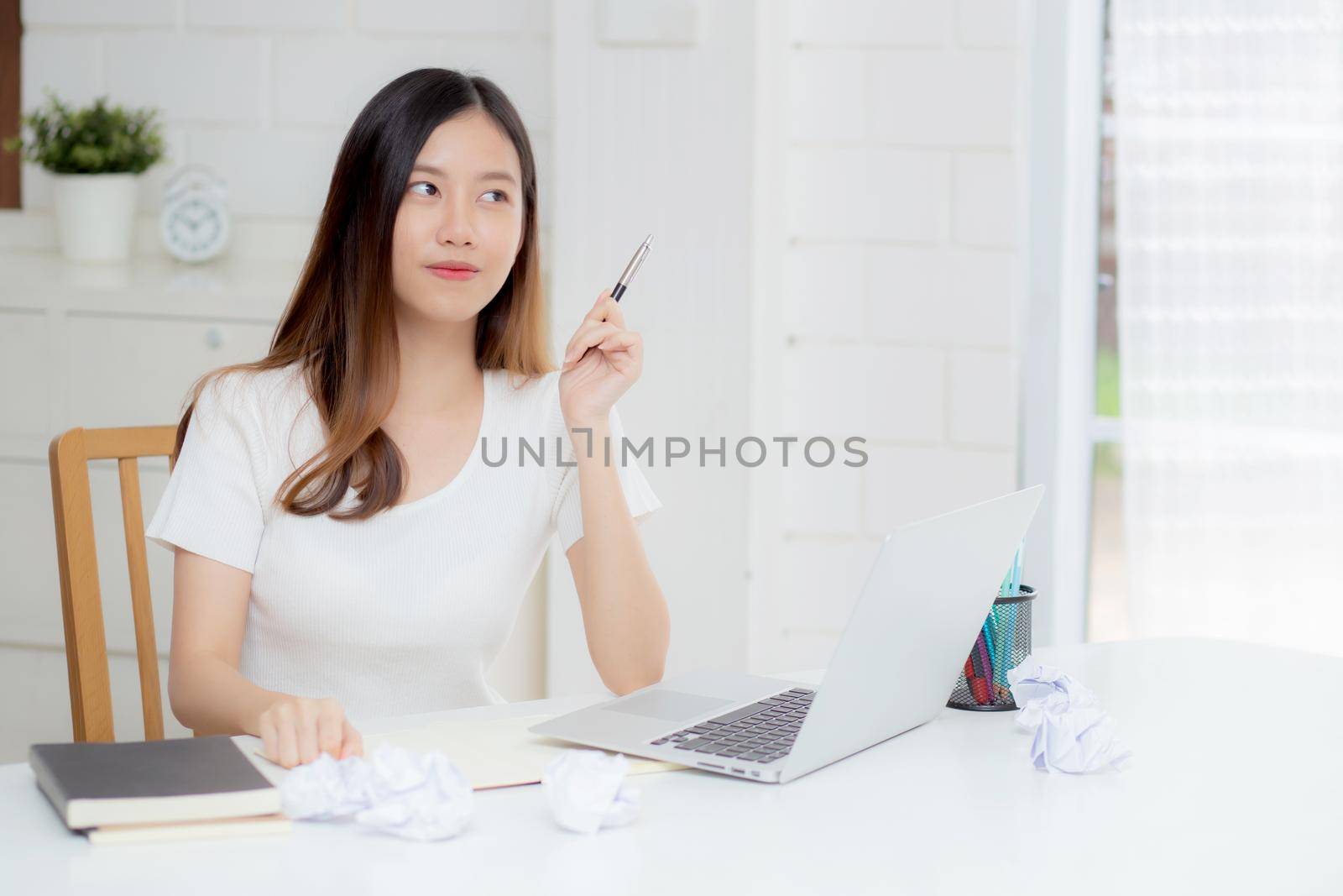 Young asian woman confident working at home with laptop computer and thinking idea for planning, freelance happy girl excited and success using notebook thoughtful and writing, business concept.