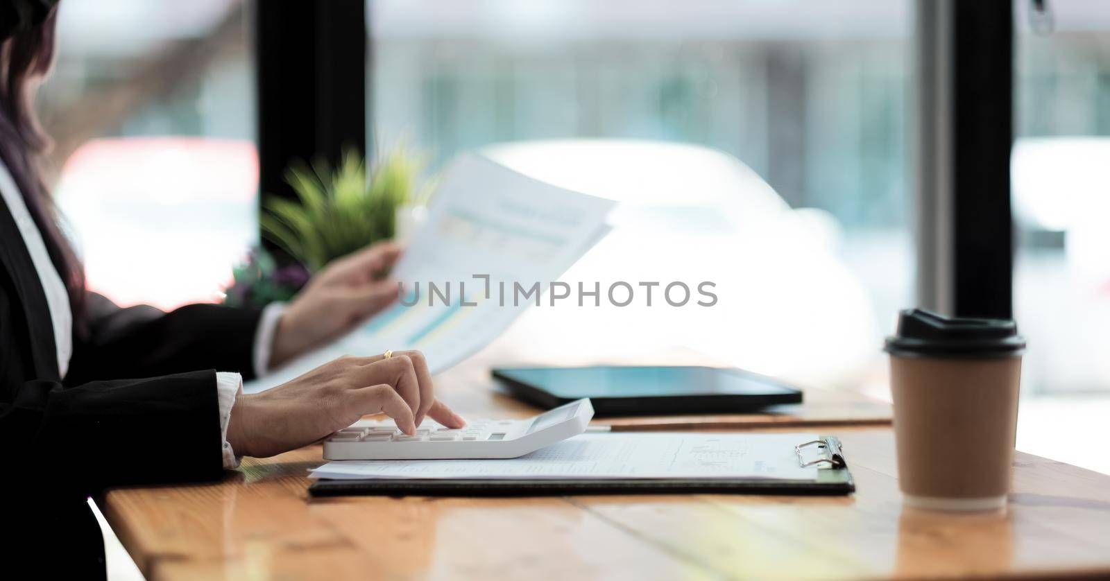 Close-up accountant using a calculator to calculate numbers on a company's financial documents, woman analyzing historical financial data to plan how to grow the company. Business Financial concept.