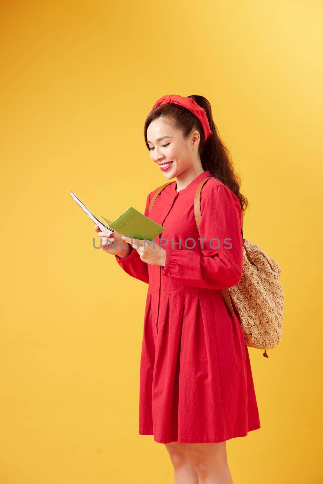 Traveler tourist young beautiful asian woman with backpack, smiling and standing on yellow background. Summer holidays, vacation and travel concept