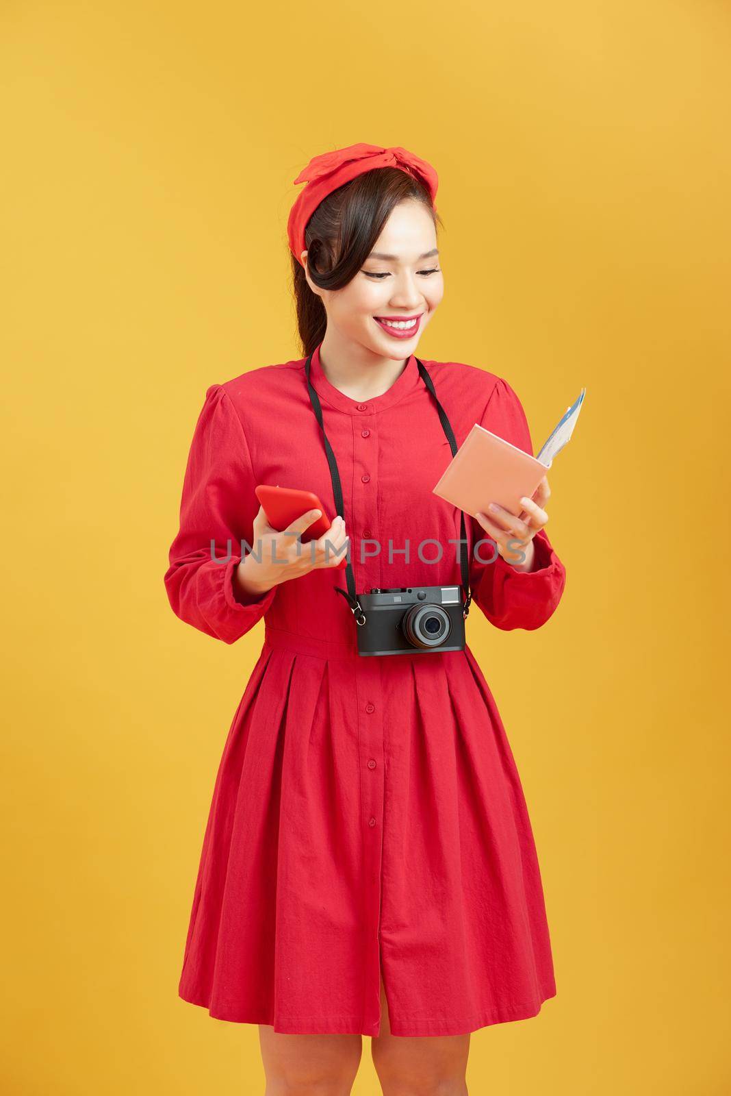 Happy woman tourist travel holding camera and passport isolated on yellow background, asian by makidotvn