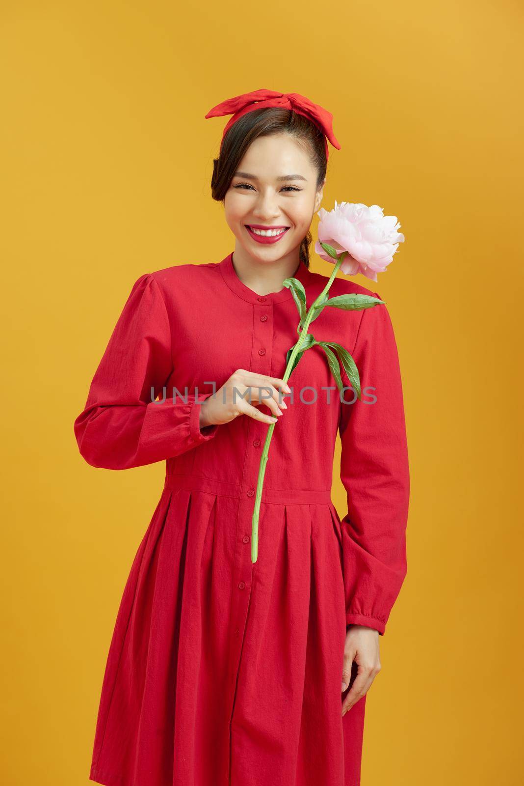 Stylish girl in white floral shirt gently holding peony flower in hands