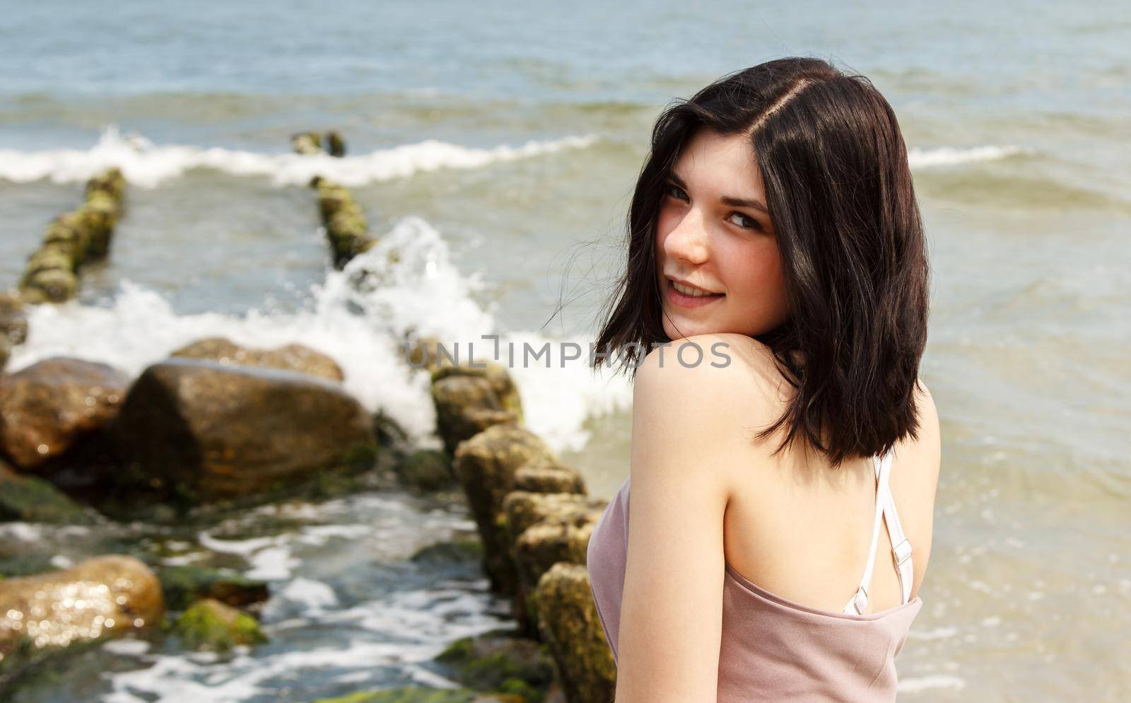 portrait of a young beautiful brunette woman by the sea on summer day