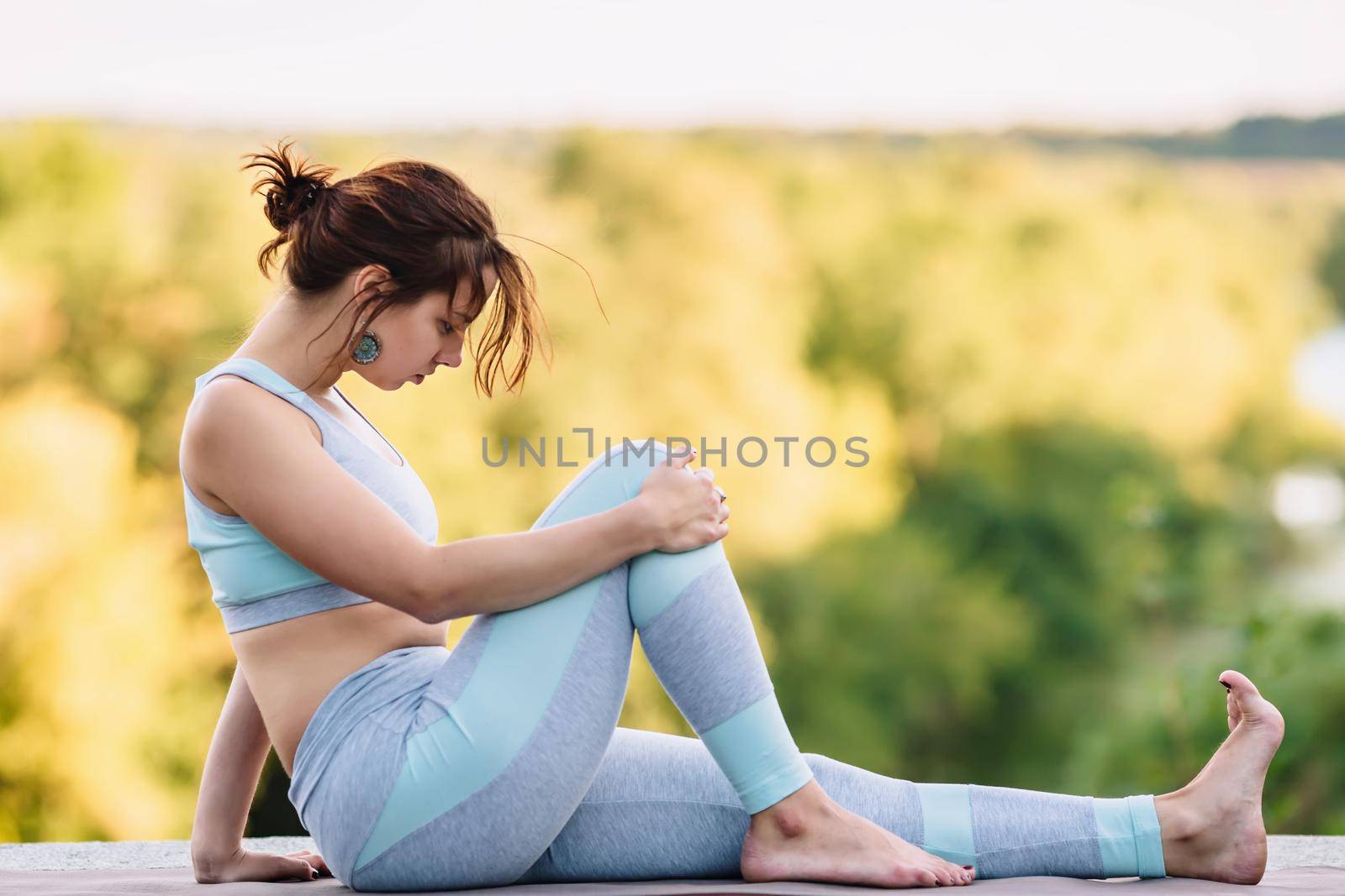 Pretty woman doing yoga exercises in the park on blurry background