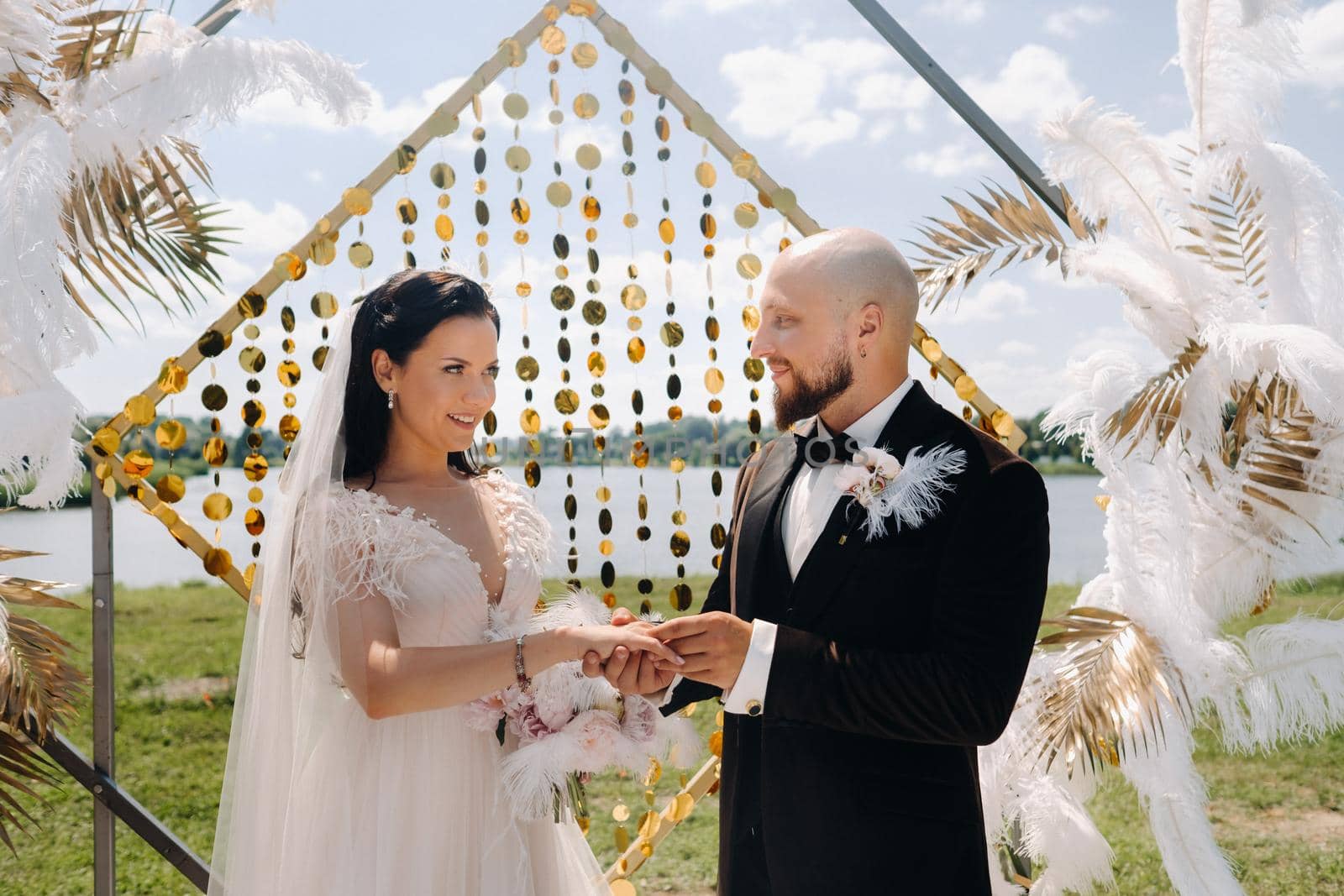 happy wedding couple near the arch wearing rings during the wedding ceremony.