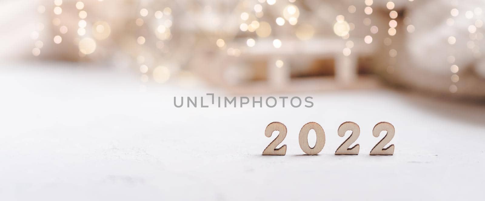 Christmas banner background or greeting card with 2022 wooden text and copy space. Glowing snow bokeh. Winter holidays on white background.