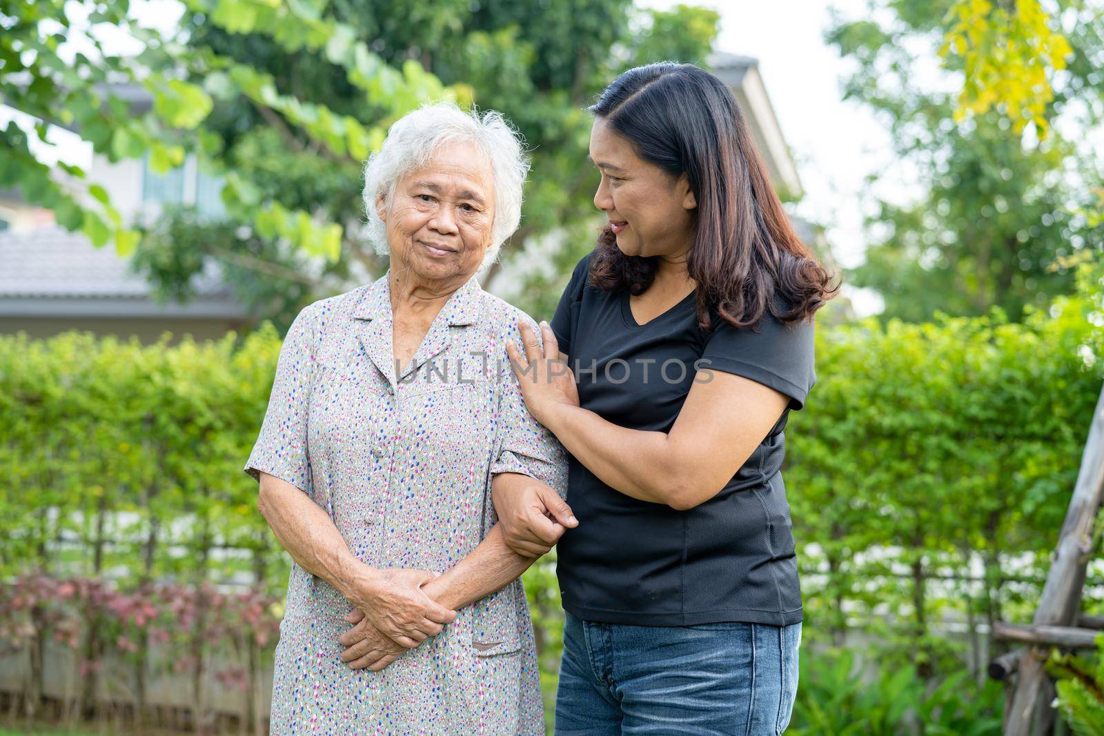 Asian elderly woman with caregiver daugther walking with happy in nature park.