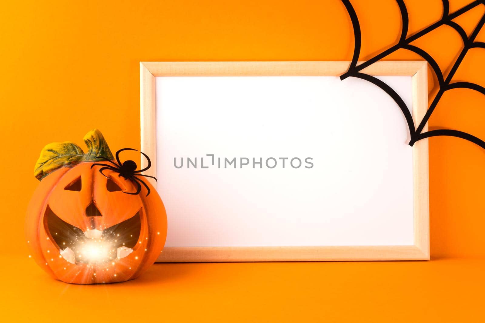 Happy halloween holiday concept. Jack o lantern, handmade paper decorations, spider, web and blank frame on orange background. Halloween festival party, greeting card with mockup copy space.