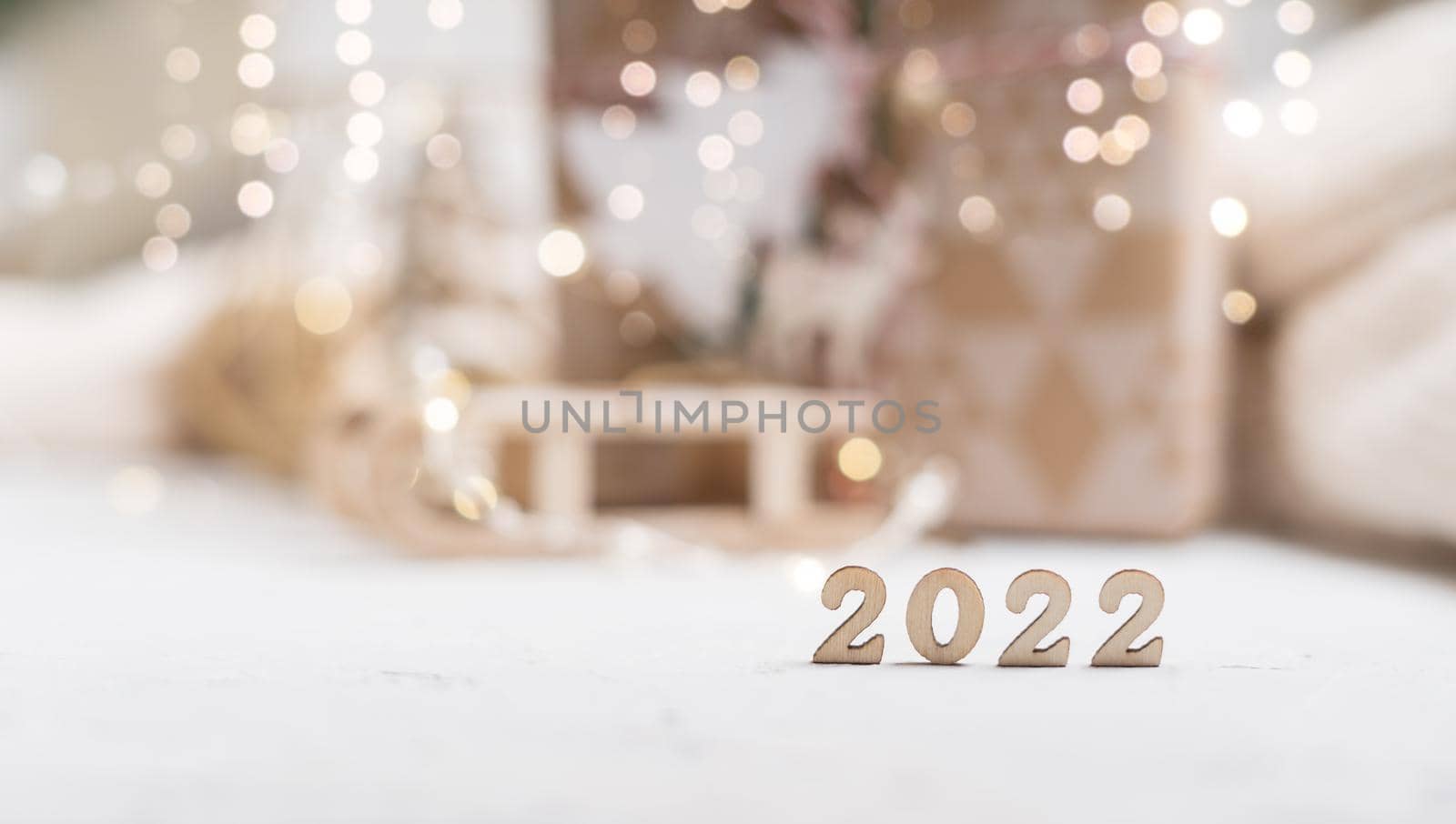 Christmas background or greeting card with 2022 wooden text and copy space. Glowing snow bokeh. Winter holidays on white background by Ostanina