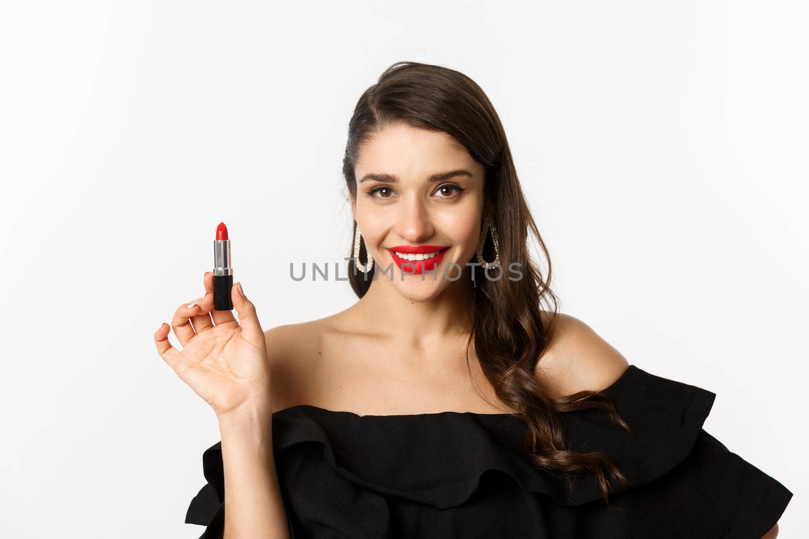 Fashion and beauty concept. Beautiful woman in black dress showing red lipstick and smiling, standing over white background by Benzoix