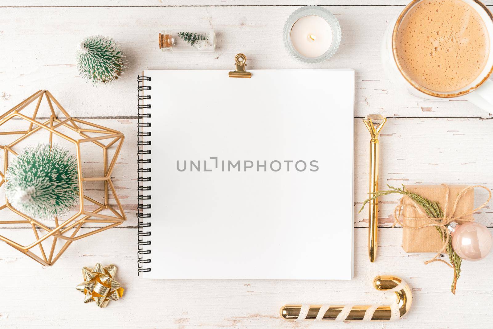 Top view Desktop Christmas notepad with mockup blank paper. Flat lay on white wooden table background with planner, coffee cup, tree brunch, Christmas eco nature decoration, notebook and stationery.