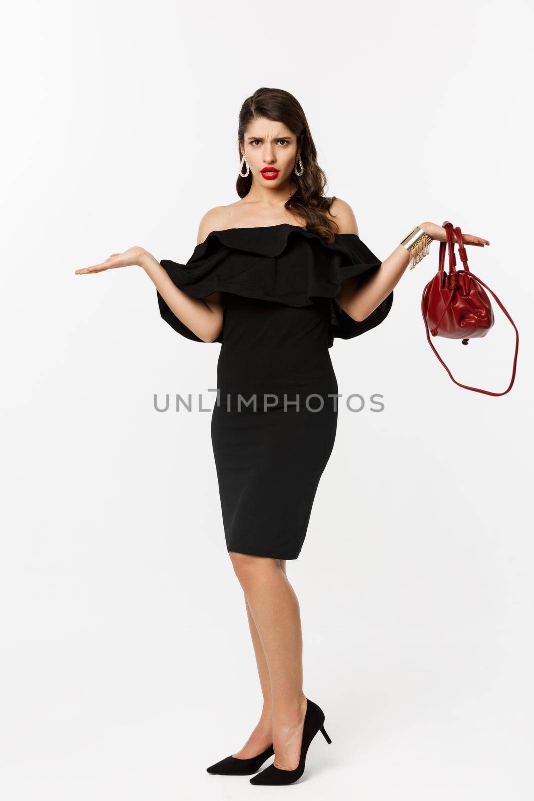 Beauty and fashion concept. Full length of disappointed glamour woman looking confused, raising hands up and staring puzzled, wearing party dress and high heels.
