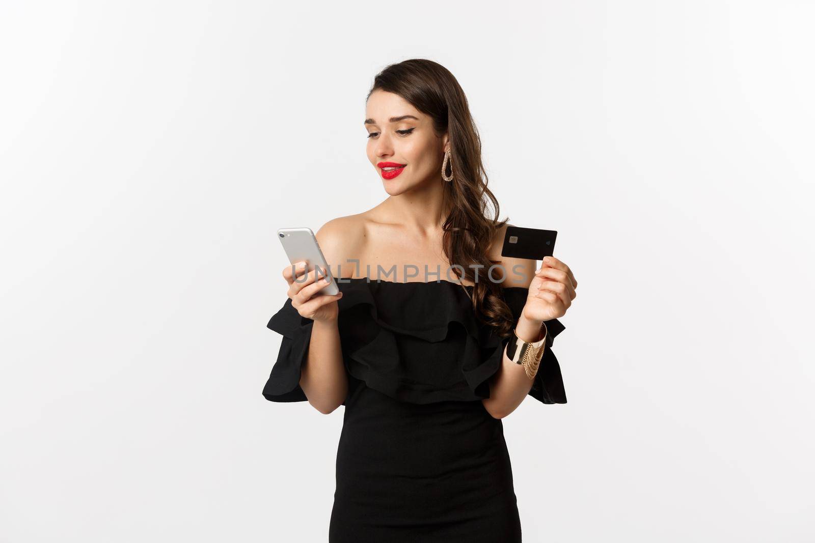 Fashion and shopping concept. Young attractive woman making purchase online, buying in internet with credit card and smartphone, white background.