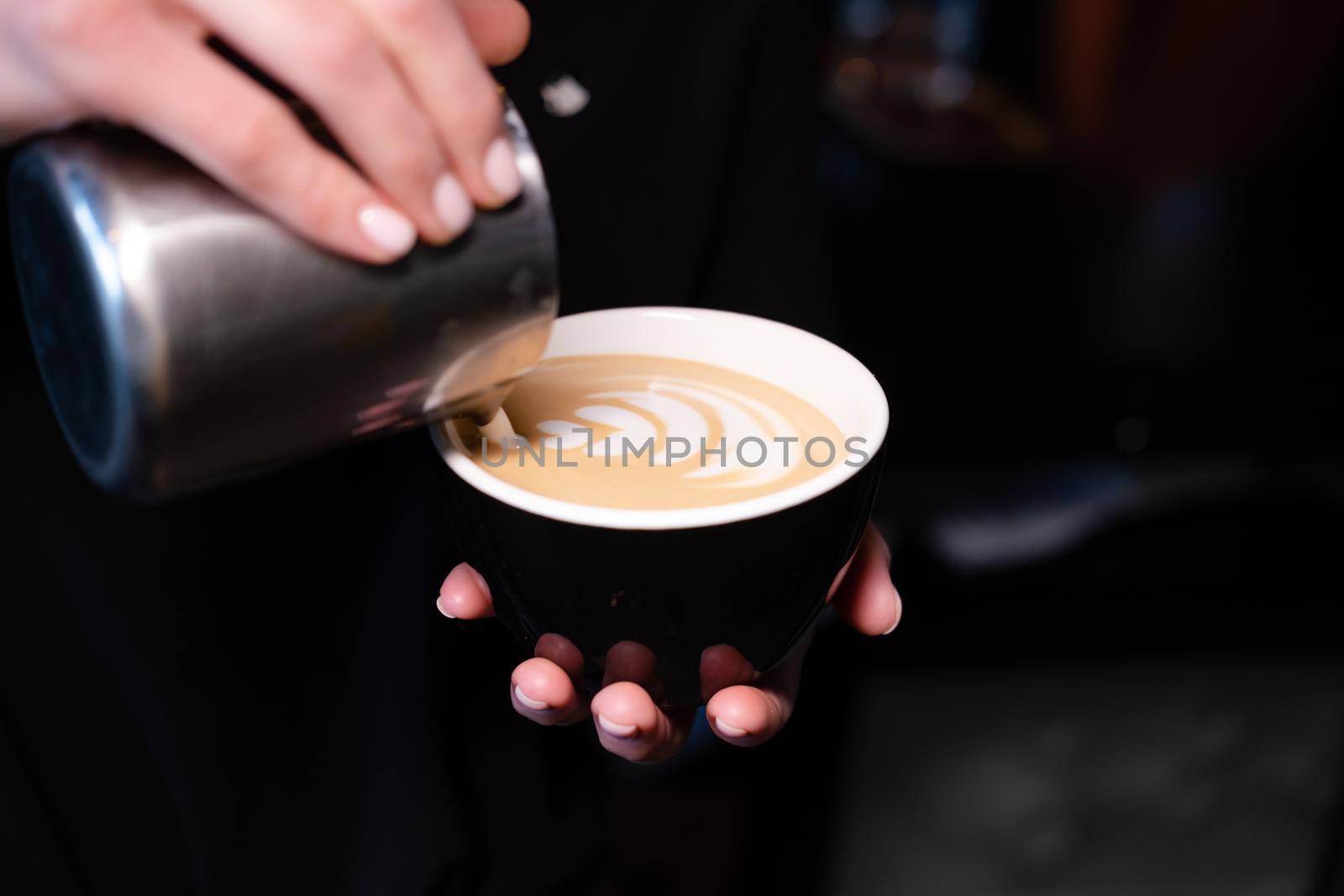 latte art by barista. pouring milk in coffee. dark coffee house.