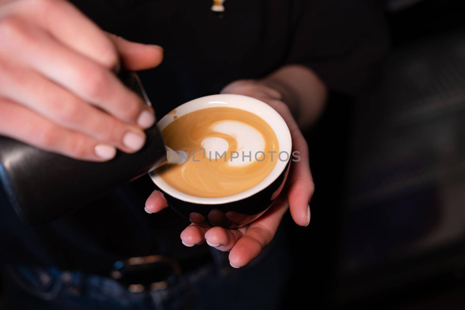 Barista pouring latte foam on coffee, espresso. creating a perfect latte art. dark colours, coffee house.