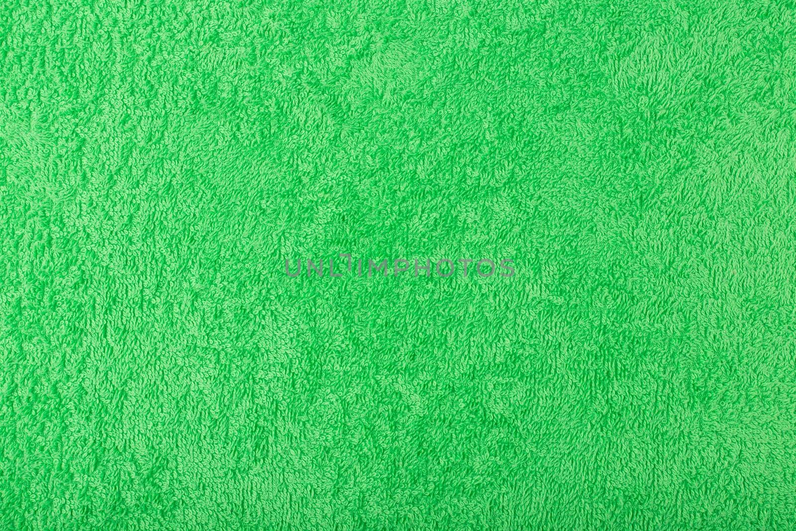 Green fuzzy and fluffy towel fabric close up. Fleece cozy shower towel background with space for text