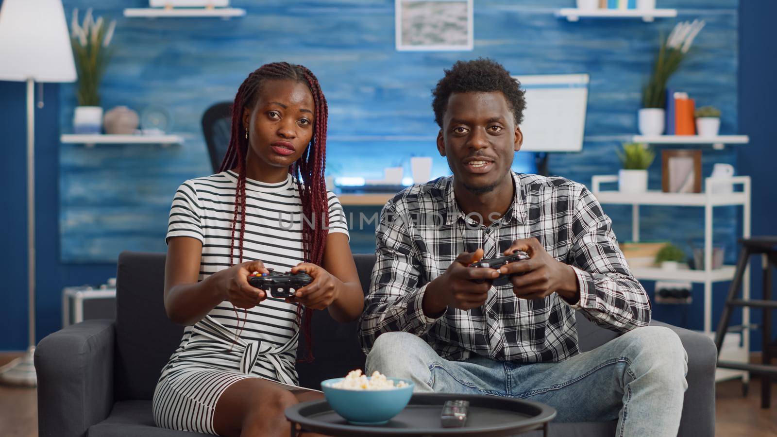 African american couple losing video game match on living room couch. Black people playing with console, controller, and television for fun activity and relaxation. Partners sitting together