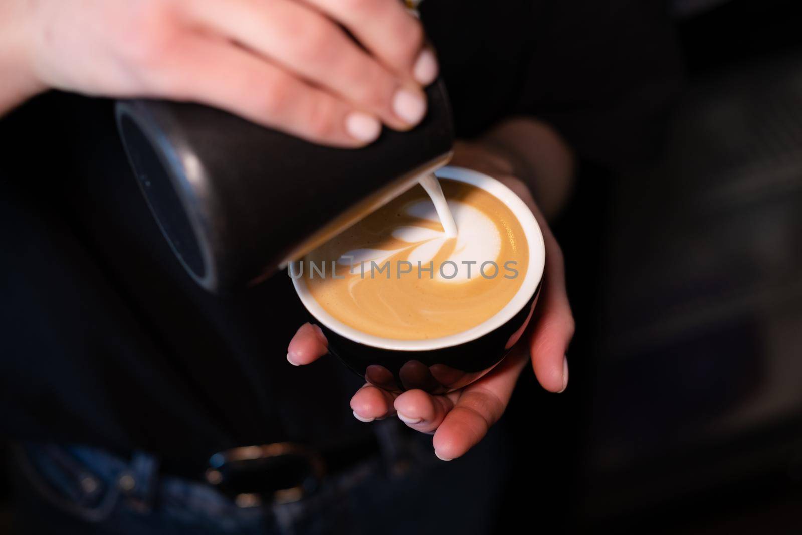 Barista pouring latte foam on coffee, espresso. creating a perfect latte art. dark colours, coffee house.