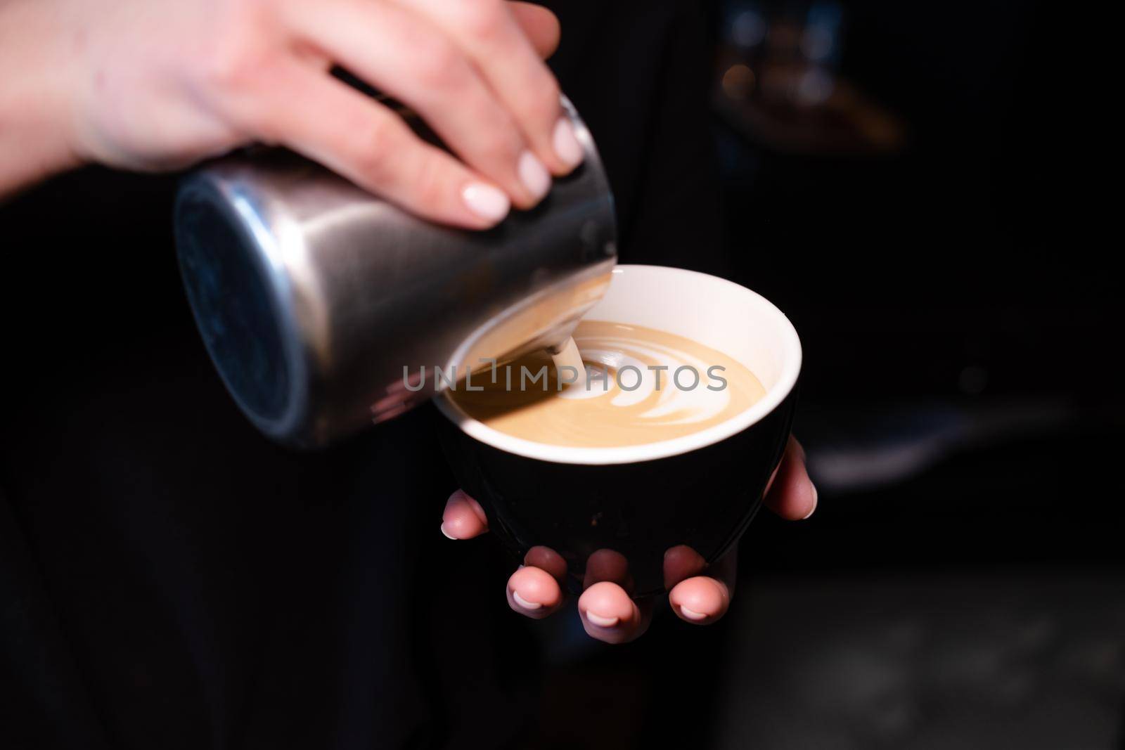 latte art by barista. pouring milk in coffee. dark coffee house.