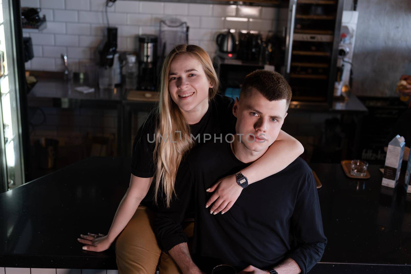 happy married couple in identical clothes family look - cafe owners or workers - in modern coffee shop. family business. loft cafe.