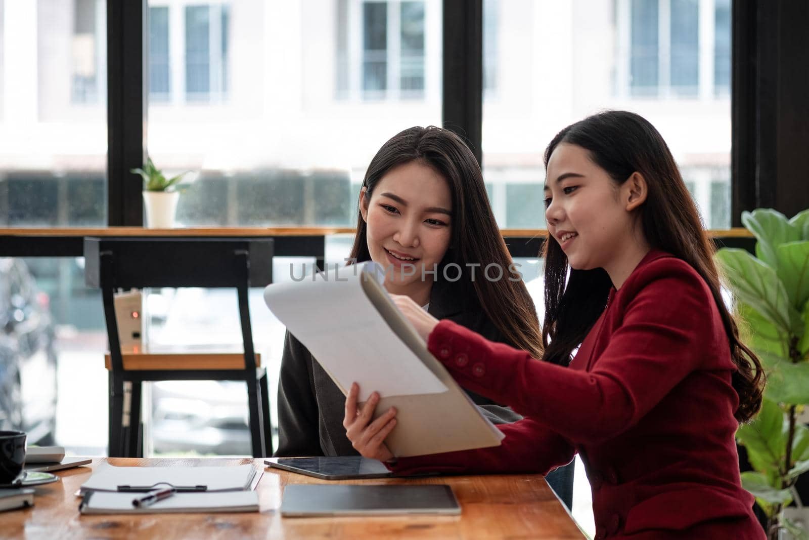 Business People Planning Strategy Analysis from financial document report, two asian female working together at office.