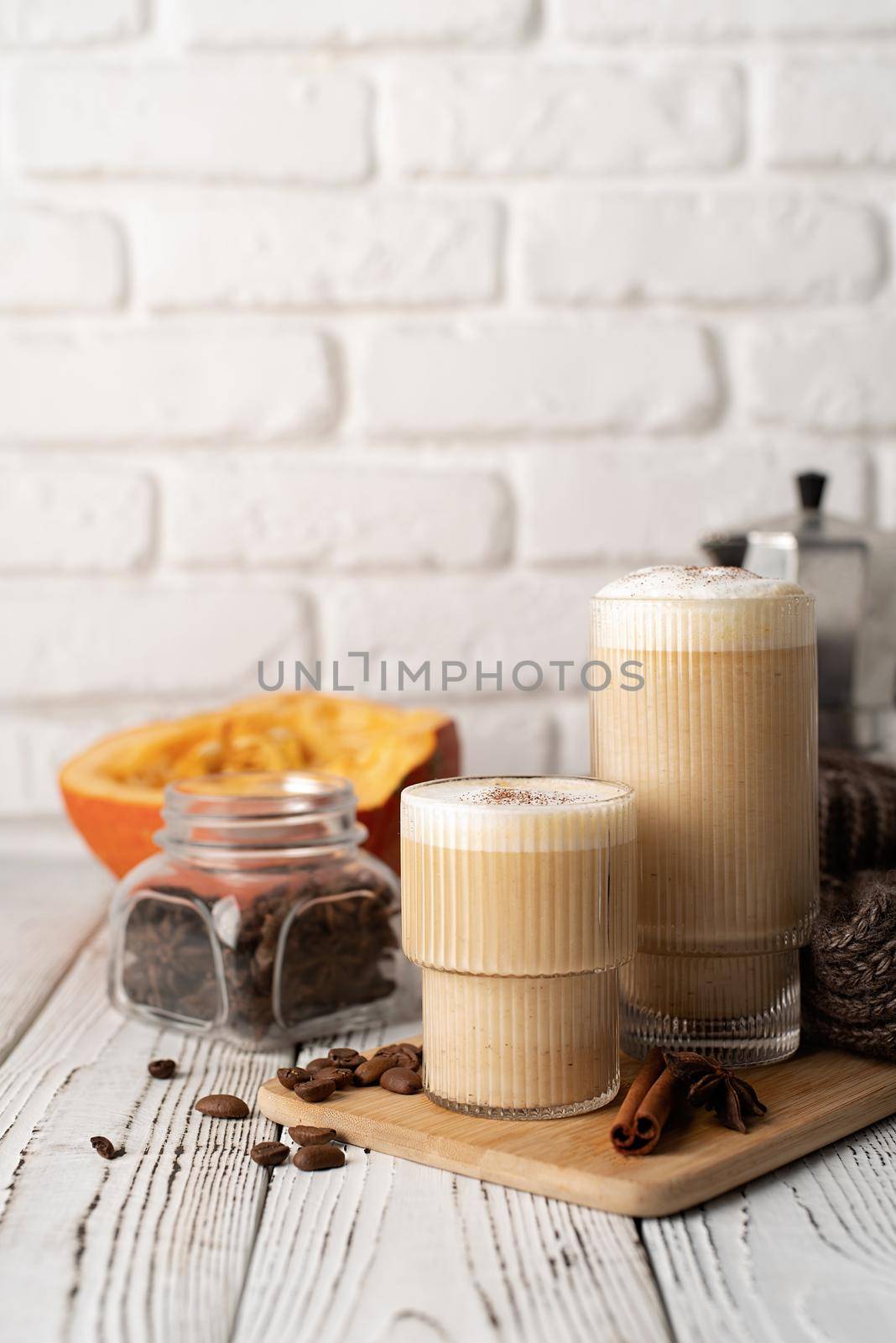 Autumn food and drink. Seasinal drinks. Pumpkin spicy latte with cream and spice, front view, white brick wall background