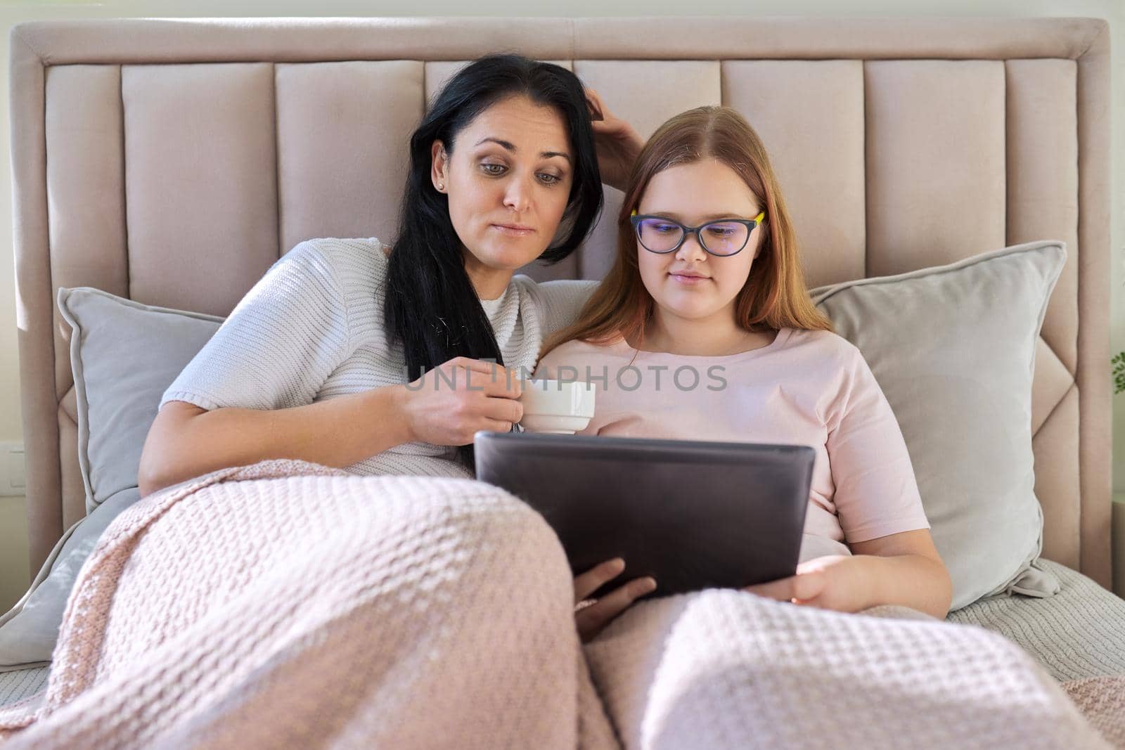 Mother and teenage daughter are resting at home together, use a digital tablet by VH-studio