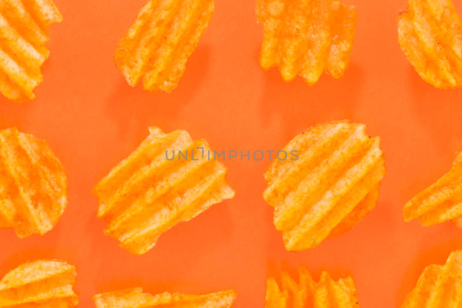 Ribbed potatoes snack with pepper on pastel orange background. Ridged potato chips on orange background. Collection. Flat lay. Close-up.