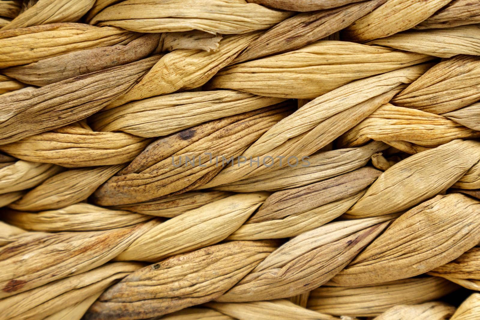 Texture of woven beige straw, background of braids from the plant stem close-up. Selective focus