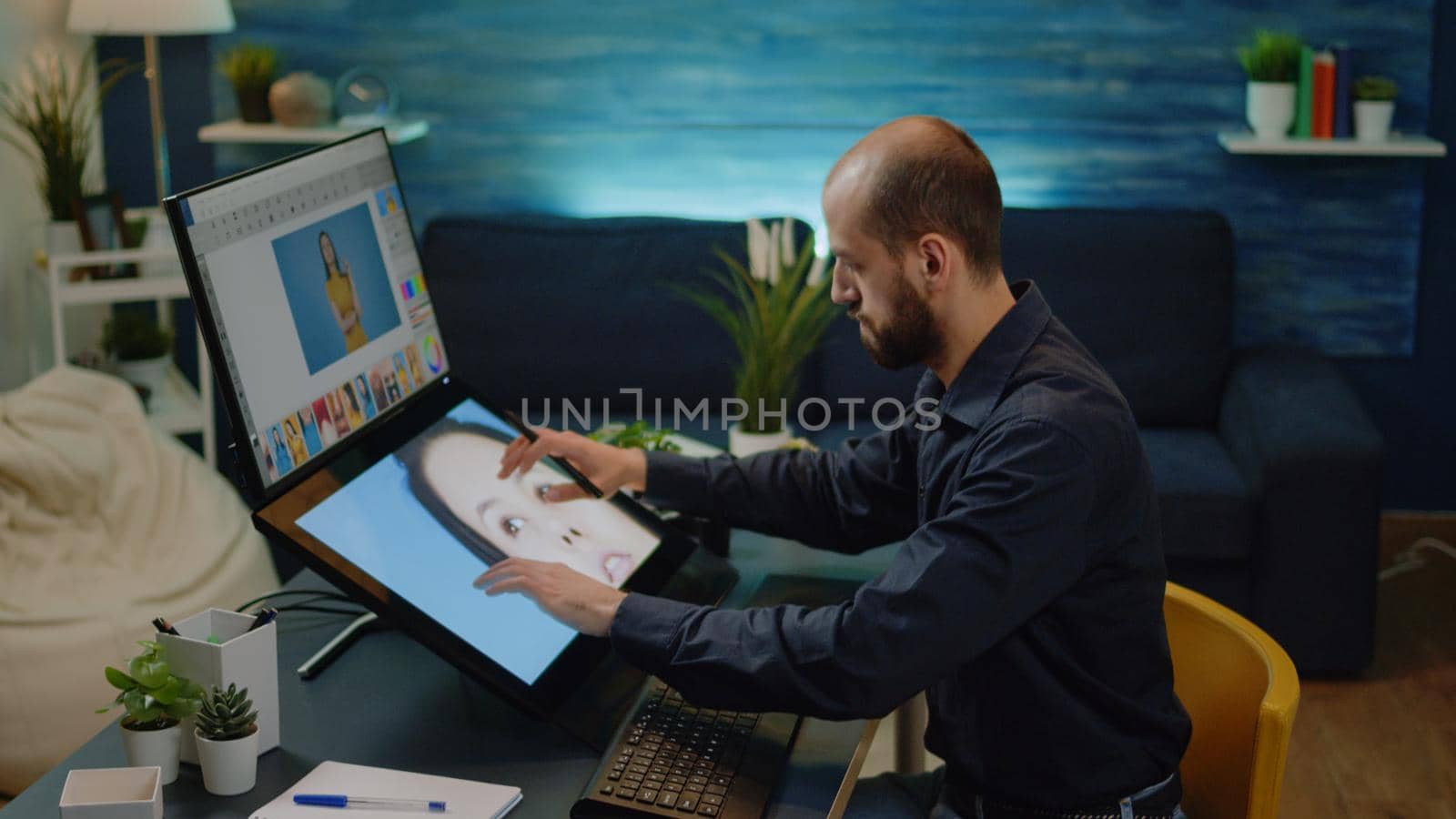 Male photographer doing editing work on touch screen monitor at studio. Photography editor working on retouching software and graphic tablet with stylus for professional pictures