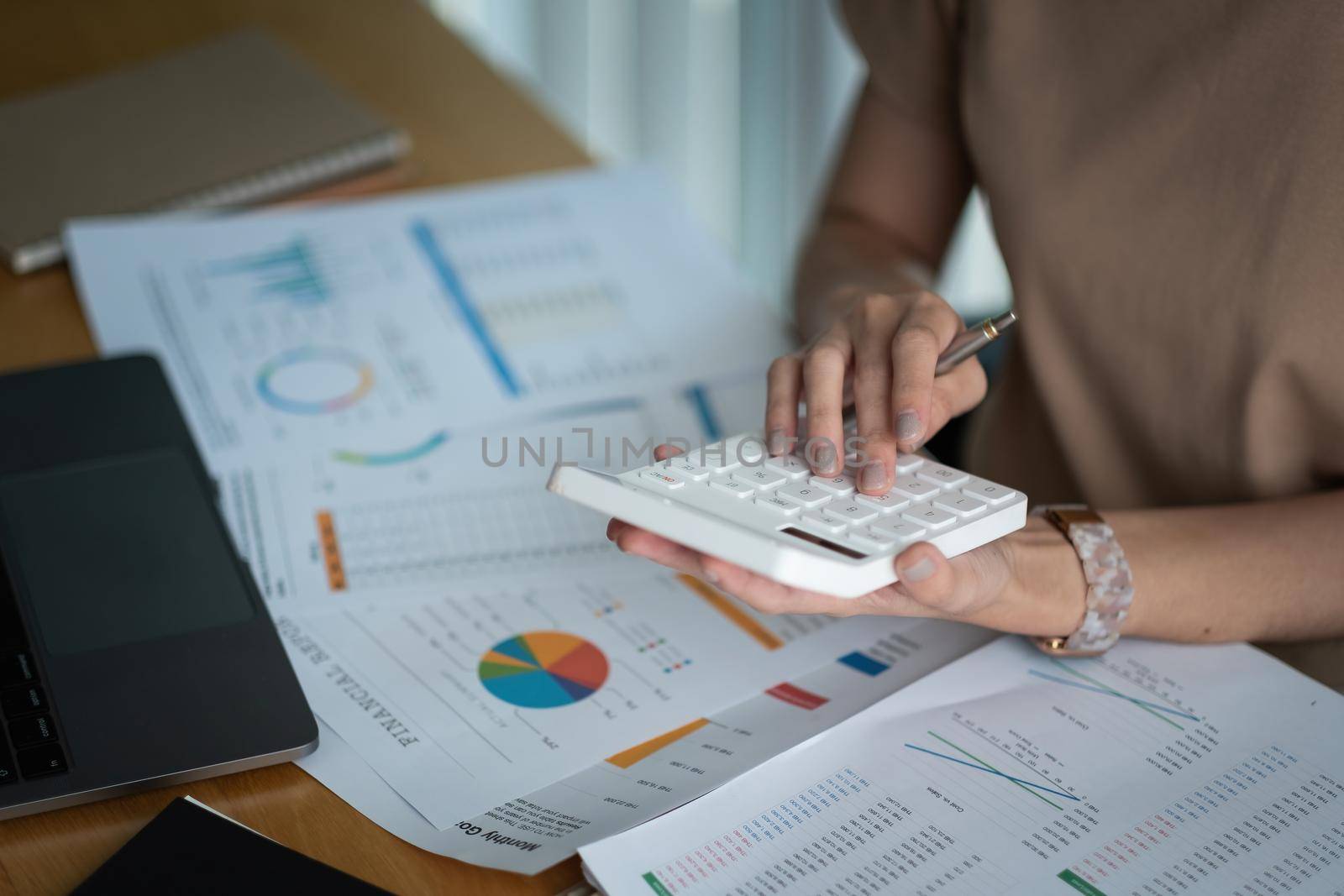 Close up Business woman using calculator and laptop for do math finance on wooden desk in office and business working background, tax, accounting, statistics and analytic research concept