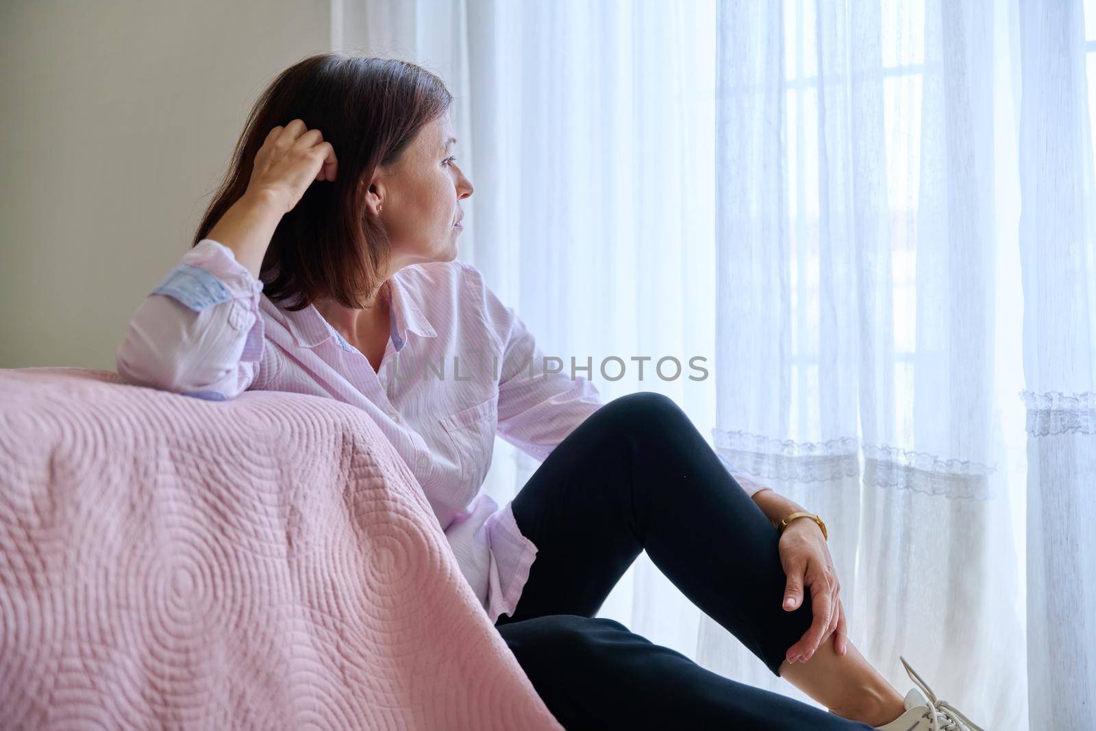 Depression, stress, sadness, mental problems, woman and health. Middle-aged sad upset unhappy female sitting on the floor near the bed at home