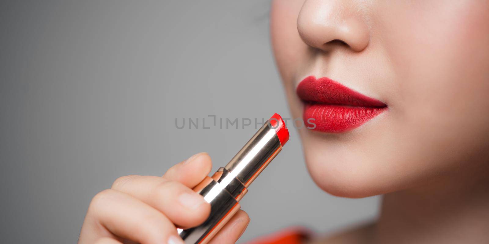 Beautiful young woman applying lipstick by makidotvn