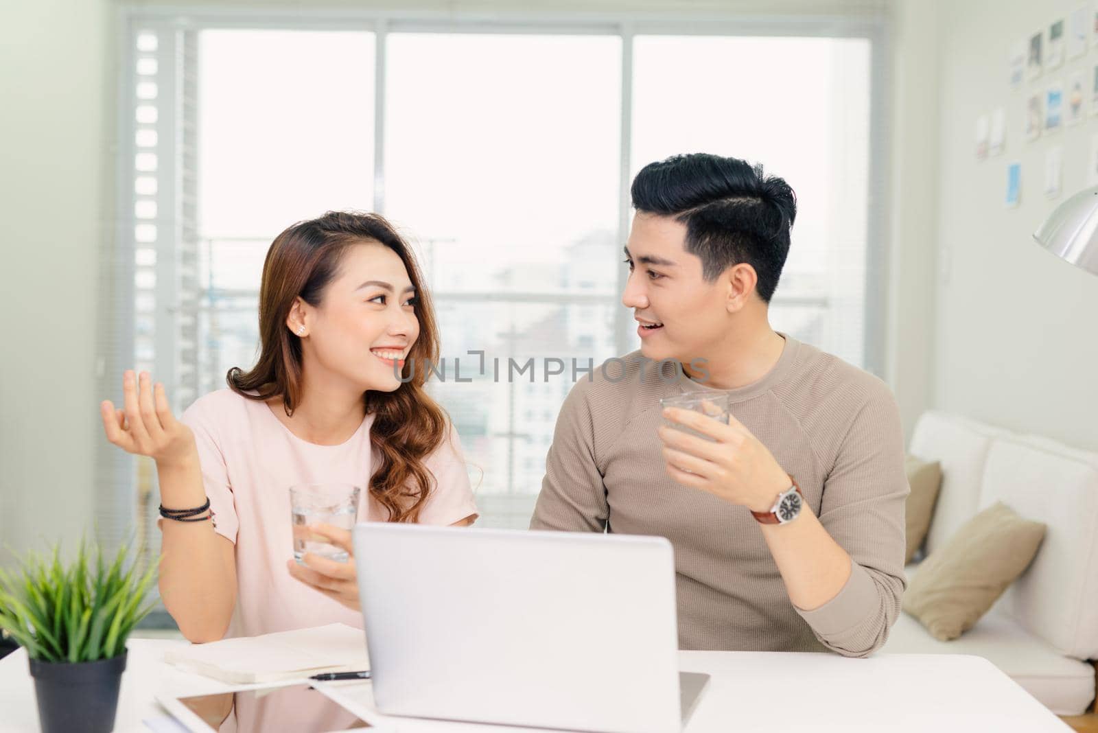 cheerful young male and female laughing while making plans for family budget communicating by makidotvn