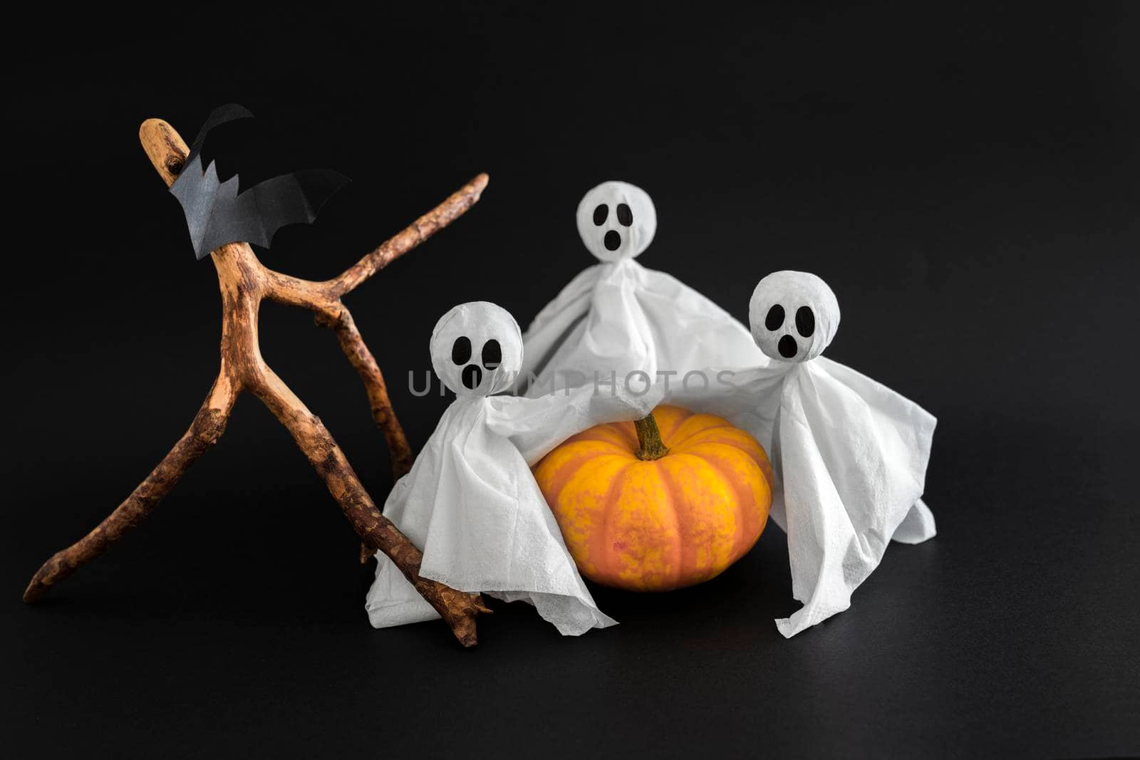 Three ghosts, bat and pumpkin on black background. Symbols of Halloween .