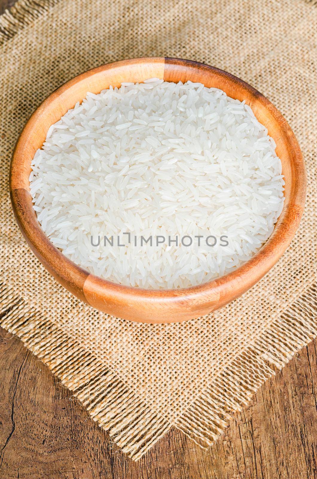Organic Thai Jasmine rice grain in wooden bowl preparing. by Gamjai