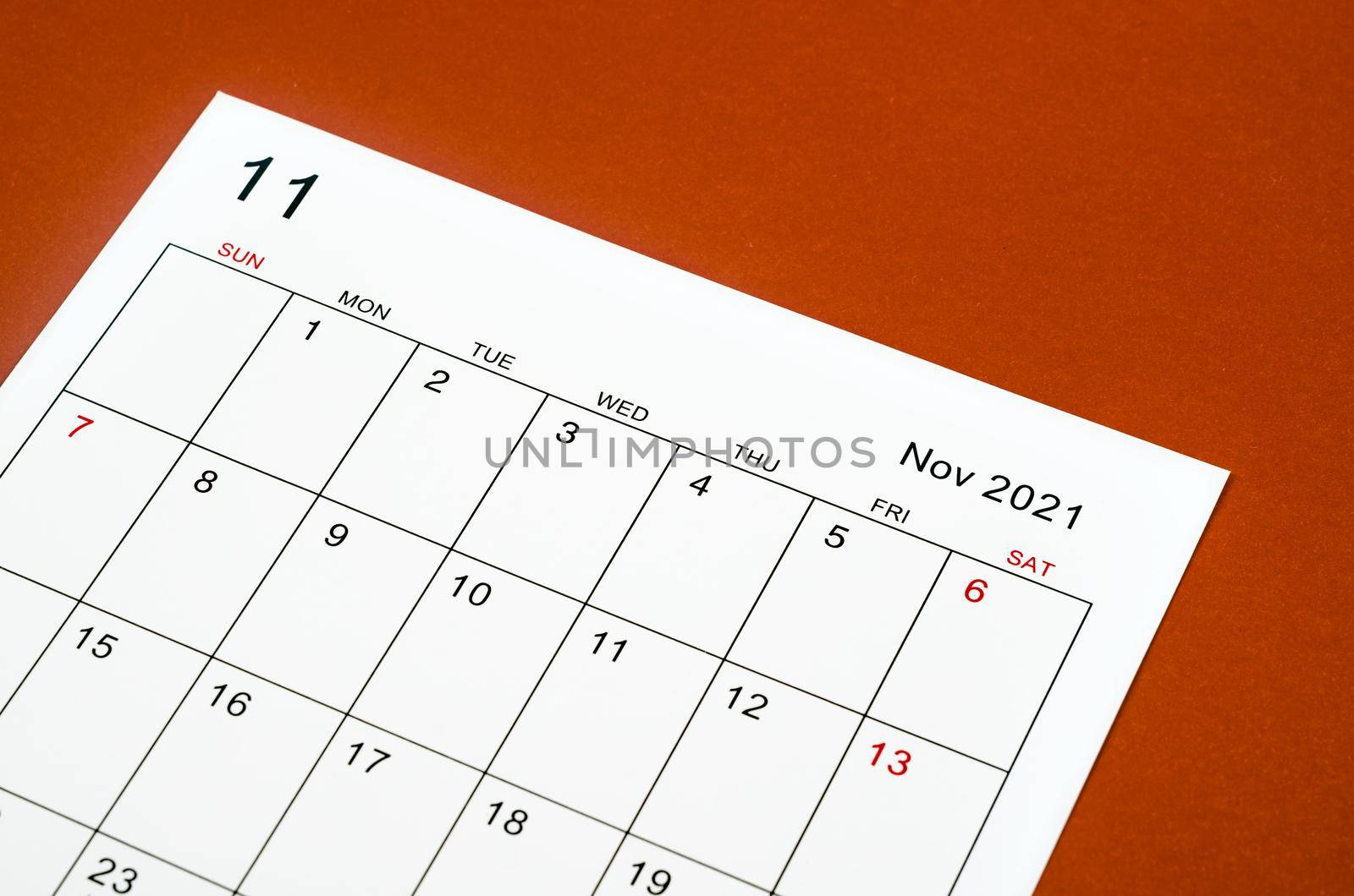 Close up November 2021 calendar sheet on red background.